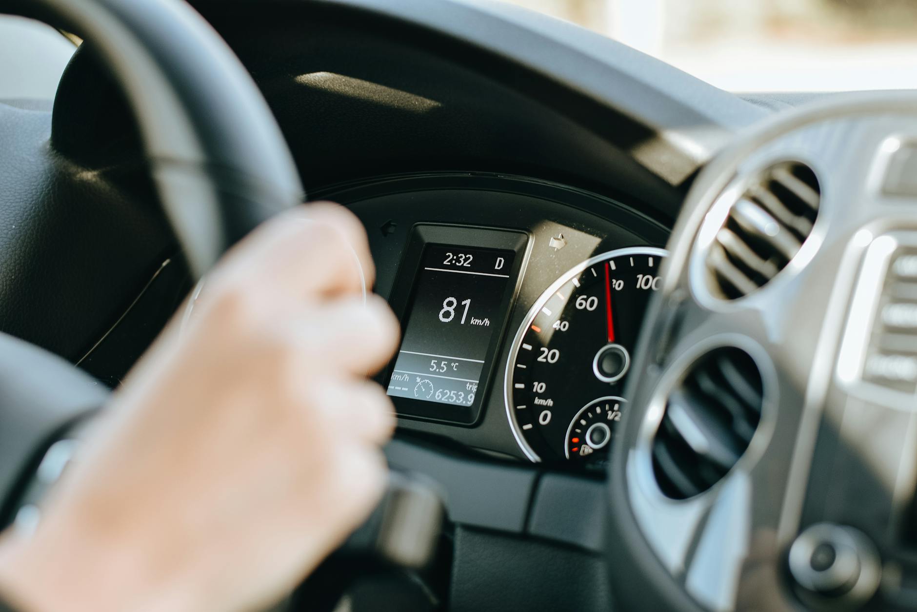 Kierowca trzyma czarną kierownicę Porsche podczas jazdy w słońcu