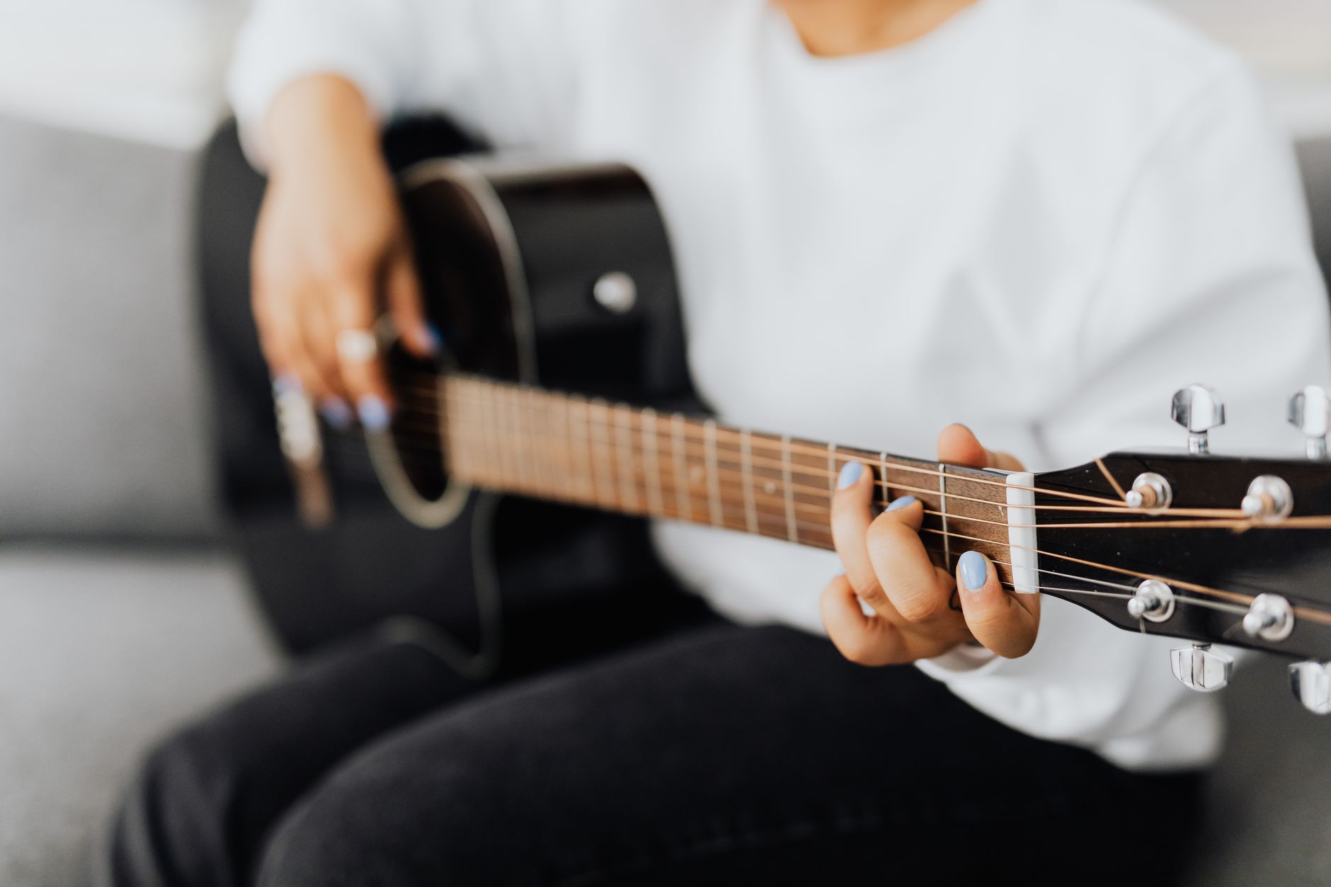 Dłoń początkującego gitarzysty na gryfie gitary akustycznej