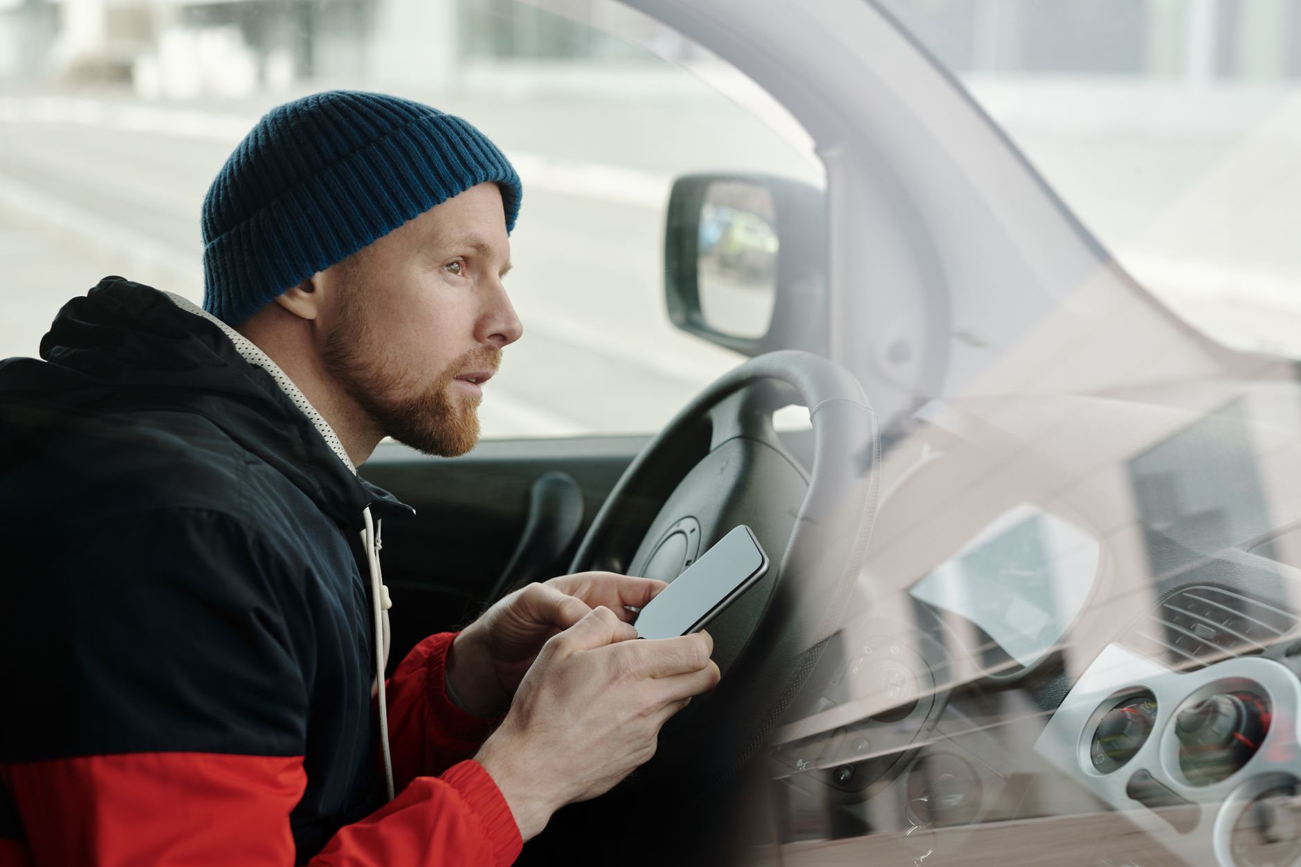 Mężczyzna w zaparkowanym Volkswagenie korzysta ze smartfona