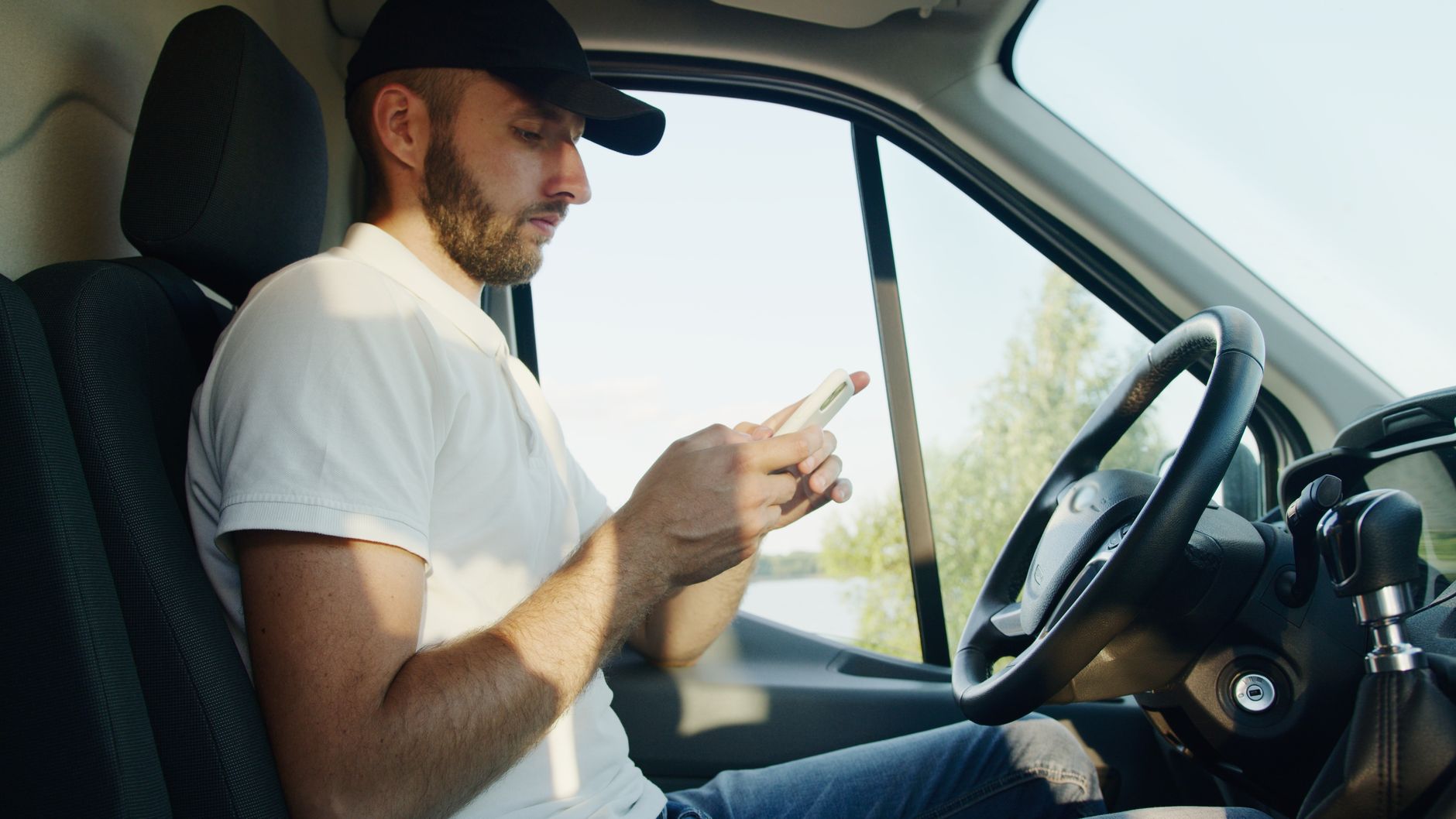 Mężczyzna w zaparkowanym Volkswagenie korzysta ze smartfona